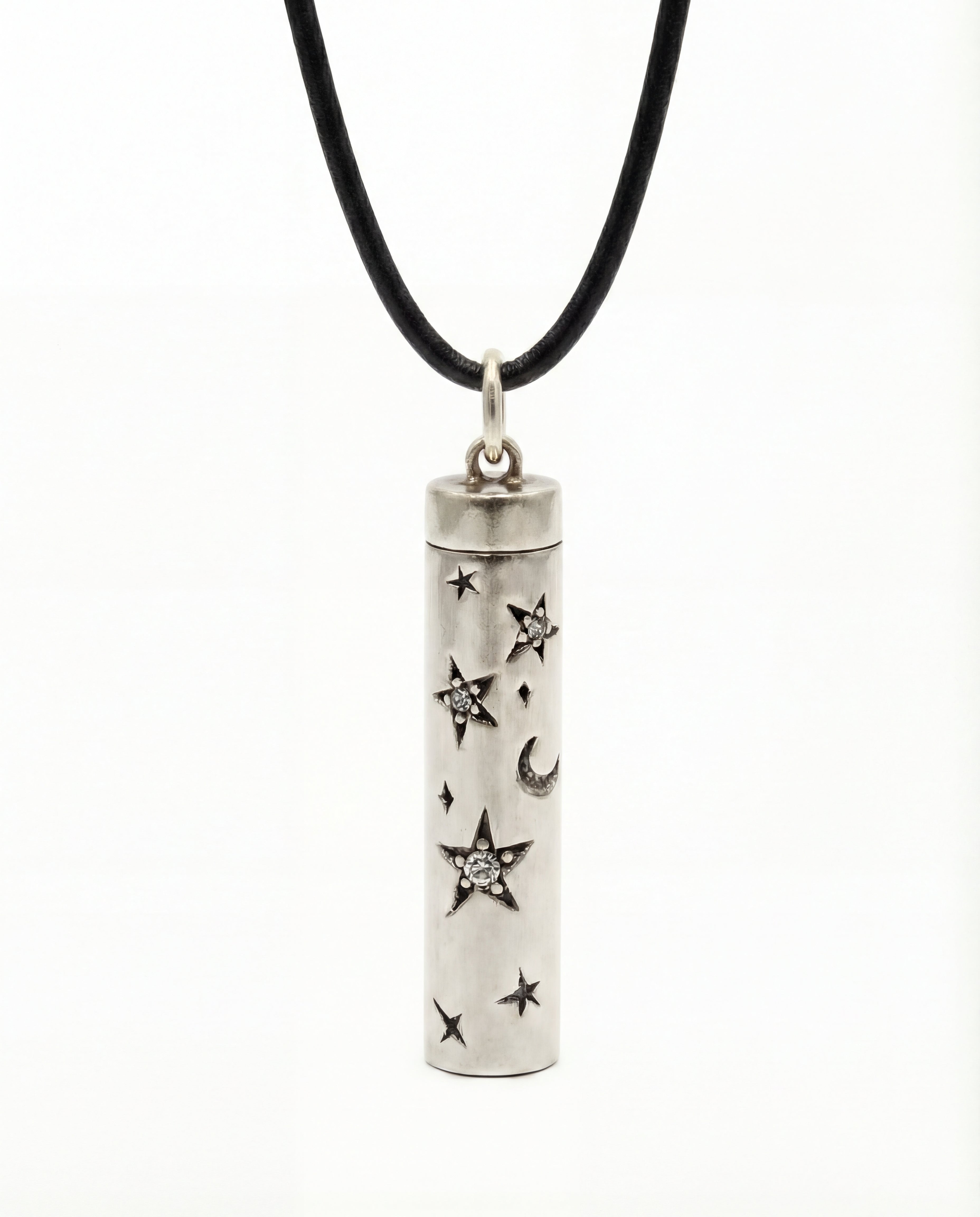 Silver cylindrical pendant with star and moon designs on a black cord against a white background