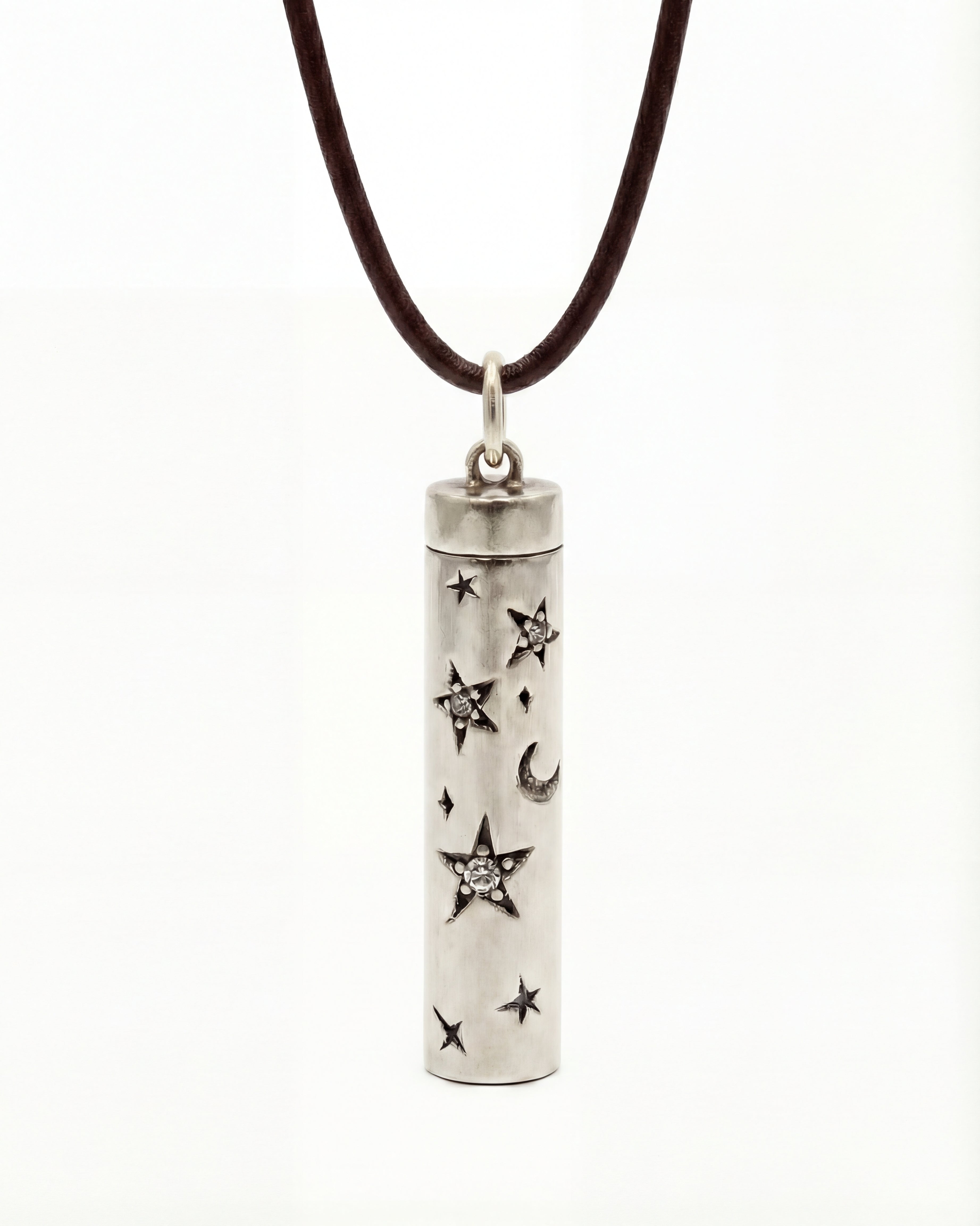 Silver cylindrical pendant with star and moon designs on a brown cord against a white background