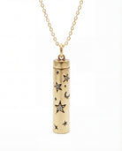Gold cylindrical pendant with star and moon designs on a white background