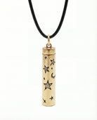 Gold cylindrical pendant with star and moon designs on a black cord against a white background