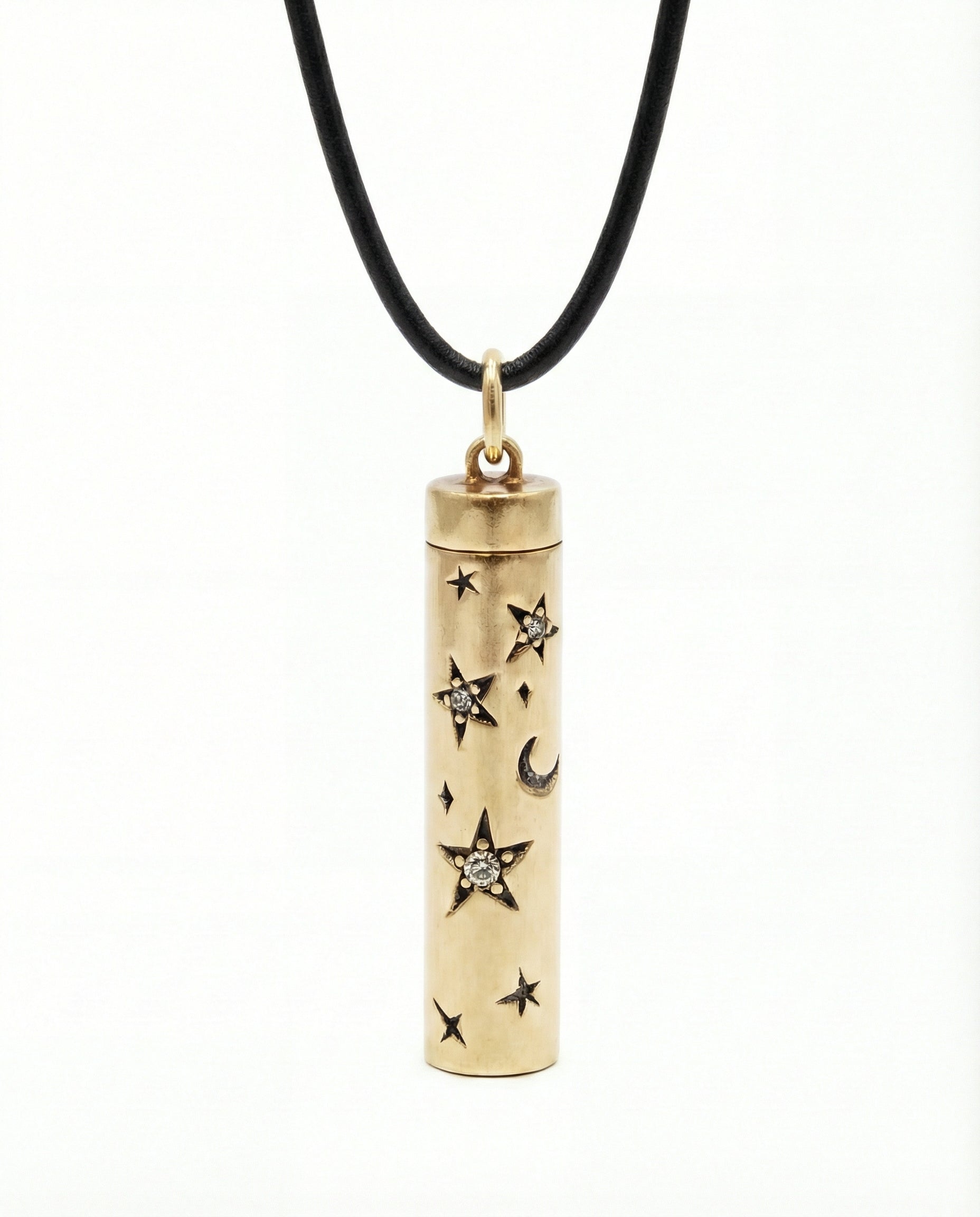 Gold cylindrical pendant with star and moon designs on a black cord against a white background