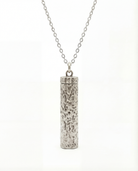 Silver cylindrical pendant on a chain against a white background