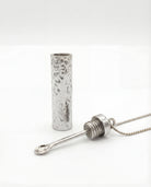 Silver cylindrical pendant on a white background