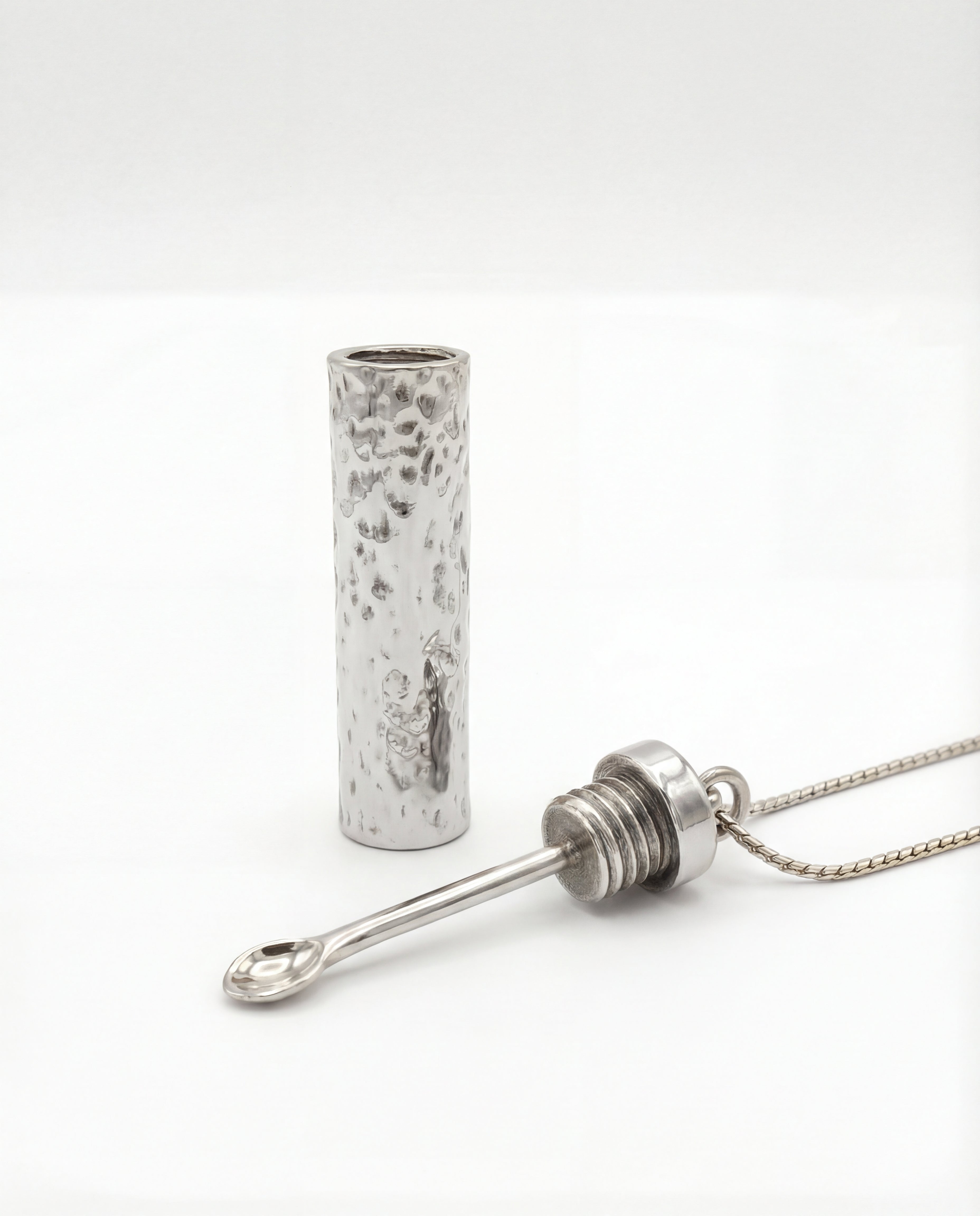 Silver cylindrical pendant on a white background