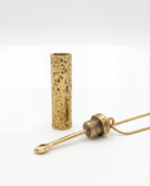 Gold necklace with a cylindrical pendant on a white background